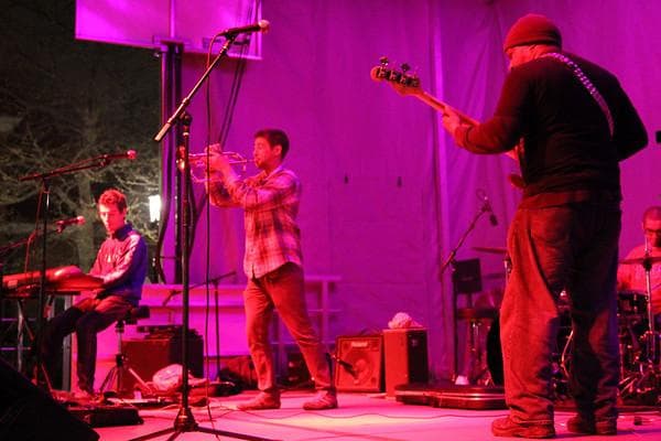 Funkharp on stage in magenta light, with keyboards, trumpet, bass, and drums.